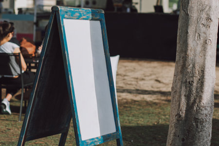 Blank board and template banner with nice blue colorful frame stands in park with a tree nearby, empty stand signage with white backgroundの写真素材