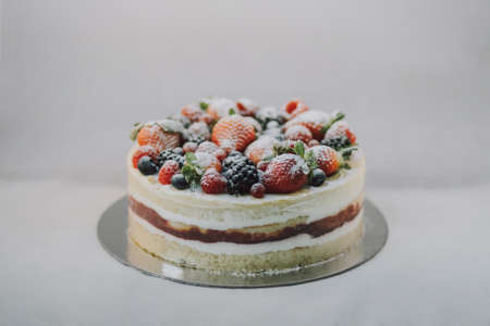 Delicious white cake with natural fruits and white powder on top on white background. Beautiful...