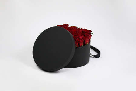 Black round gift flower packaging box with red roses inside and opened lid. Stylish flower...