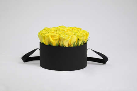 Black round gift flower box with yellow roses inside. Stylish flower arrangement.