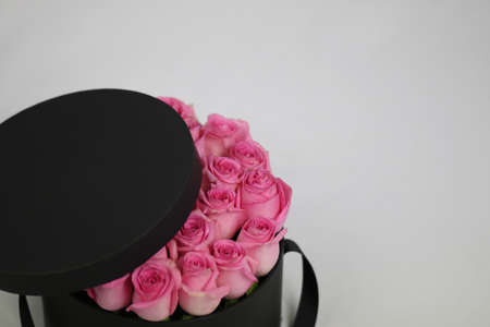 Black round gift flower packaging box with pink roses inside and opened lid. Stylish flower...