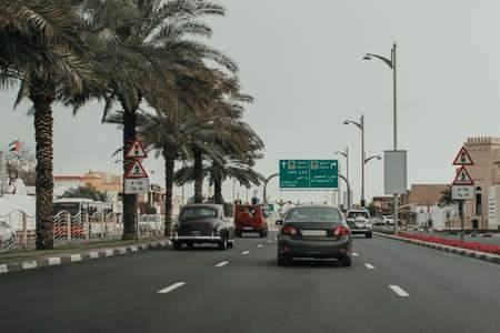 Dubai Jumeirah road car traffic with many cars, direction road boards, palm trees, traffic lights and sightseeing objectsの写真素材