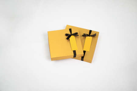 Isolated yellow packaging cardboard box containers with decoration and ribbon on white background