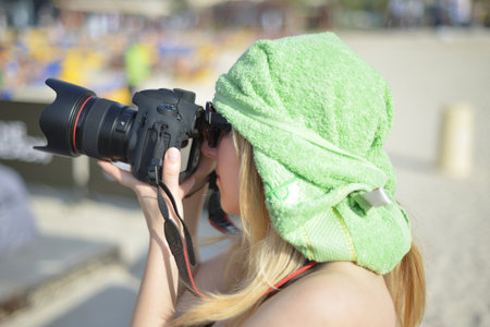 Young woman photographer taking photos outdoor on digital camera at a daytimeの写真素材