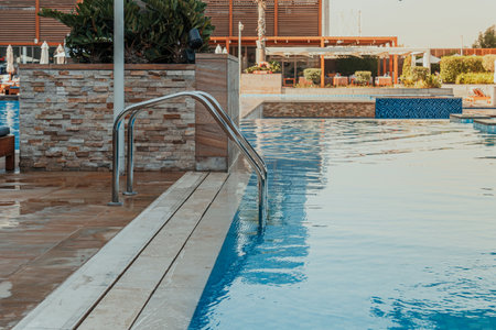 Luxurious swimming pool with stainless steel ladder and modern poolside area