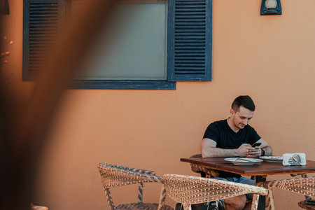 Man seating outdoor at Mediterranean style cafe while using smartphoneの写真素材
