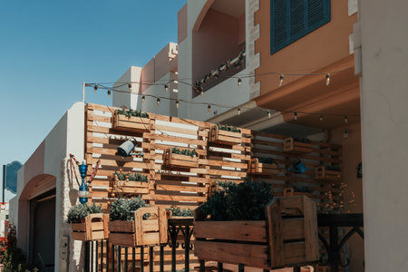 Rustic outdoor seating area with wooden planters and string lights at a Mediterranean-style buildingの写真素材