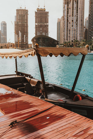 Dubai, UAE - February 12, 2020: Traditional abra boat docked at Dubai Fountain with modern skyline backdropのeditorial素材