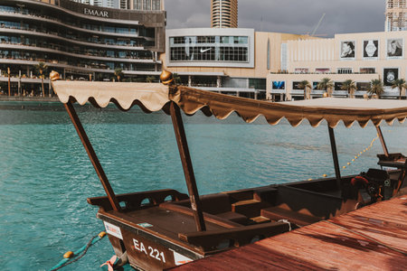 Dubai, UAE - February 12, 2020: Traditional abra boat docked at Dubai Fountain with modern skyline...