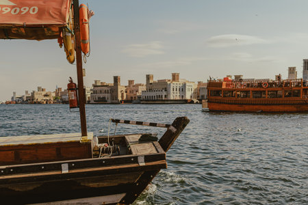 Dubai, UAE - January 6, 2020: Wooden dhow boat docked at Dubai Creek with Al Fahidi historical...