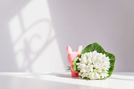Easter pink bunny, rabbit with spring flowers, a bouquet of snowdropsの写真素材