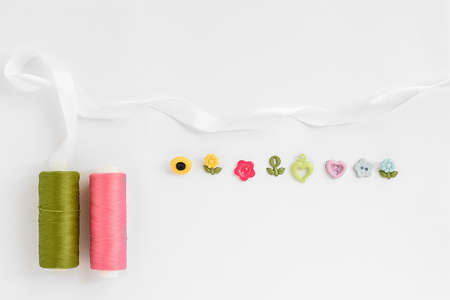 Sewing accessories on a white background. Sewing threads, pins, fabric, buttons. Top view, flat lay. Spring colorの写真素材