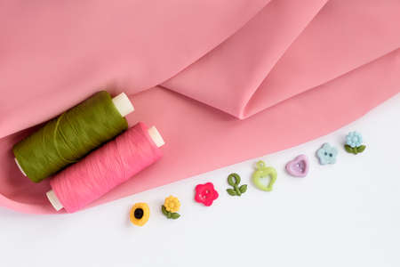 Sewing accessories and fabric on a white background. Sewing threads, pins, fabric, buttons. Top view, flat lay. Spring colorの写真素材
