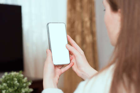 a woman holding phone showing white screen on top view, workplace home. Mockup for design, copy spase.の写真素材