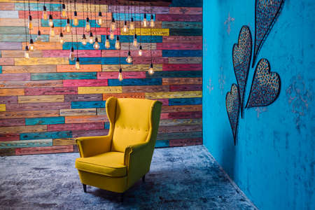 beautiful lounge room, yellow armchair, lamps and decorated wall, studio interior.の写真素材