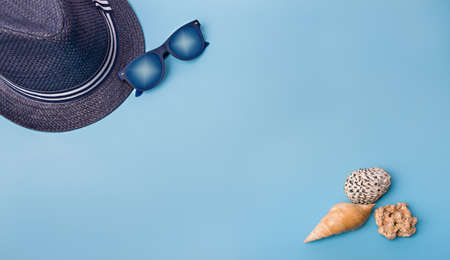 Flat lay of shells on a blue background. Seashells and hat on a pastel background. Vacation conceptの写真素材