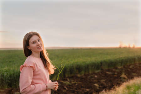 Portrait of a beautiful girl on very green meadow watching the sunset enjoying nature summer evening...