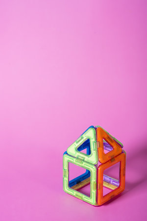 children's magnetic designer for development of motor skills, thinking and imagination. construction assembled from multi-colored parts of children's magnetic designer on pinkの写真素材
