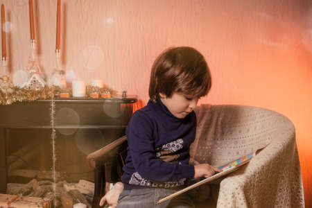 Christmas Child Happy Baby Boy reeding a book, Magic Light in Box, Kid sitting front of Xmas Treeの写真素材