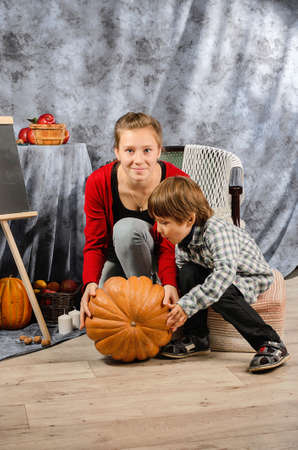 boy holding a basket with autumn harvest of nuts, red apples on the table, autumn season, autumn 2021の写真素材