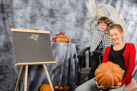 boy holding a basket with autumn harvest of nuts, red apples on the table, autumn season, autumn 2021の写真素材