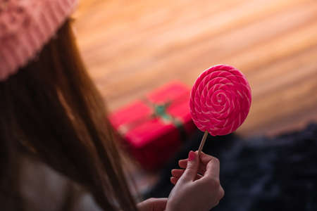 Close up girls hand with big lolipop. Festive Christmas background. New year 2022 at home.の写真素材