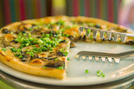 taking slices of pizza. Table with pizza in a restaurant. Pizza and hands close up on a green background.の写真素材