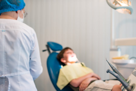 Boy visiting dentist. Handsome boy opening mouth while visiting dentist, in the dental chairの写真素材