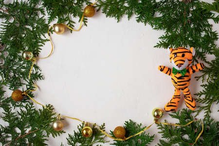 Christmas or New Year background: fir branches on a white background with Christmas balls and the symbol of the year - a tiger. White frame for congratulationsの写真素材