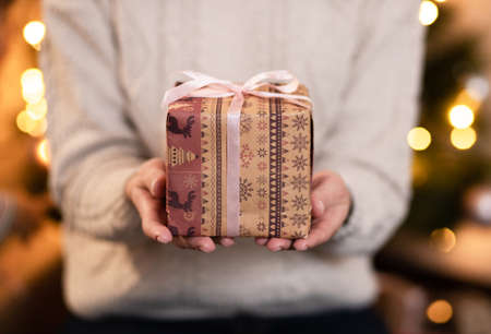 Woman's hands hold christmas or new year decorated gift box