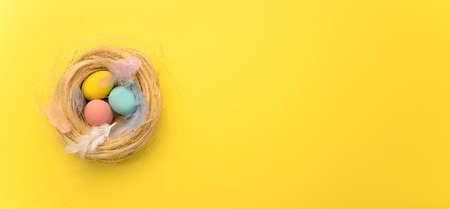 Happy Easter card. colored pink easter eggs on a yellow nest background from above, image with selective focus. Place for textの写真素材