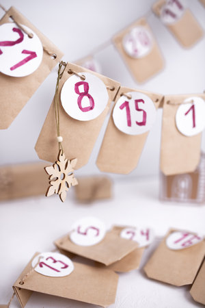 Hand made advent calendar. Preparation to christmas concept. Craft envelopes arranged on a white wall. Selective focus.の写真素材