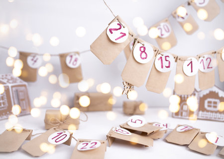 Hand made advent calendar. Preparation to christmas concept. Craft envelopes arranged on a white wall. Selective focus.の写真素材