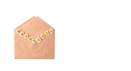 Yellow wenvelope with camomile on blue wooden background. Top view. Greeting card concept for valentines day, wedding or mothers day, womens day.の写真素材