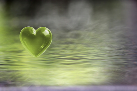 Green heart on soft focus water backgroundの写真素材