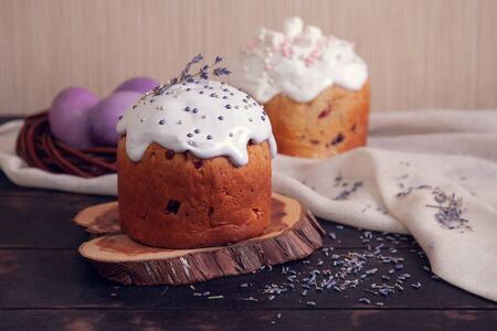 Easter cakes decorated with lavender and marshmallows and painted Easter eggs in a wicker nest.の写真素材