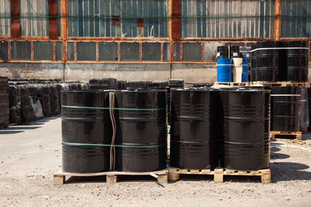 Engine oil in black barrels are stored in several rows in the warehouse.の写真素材