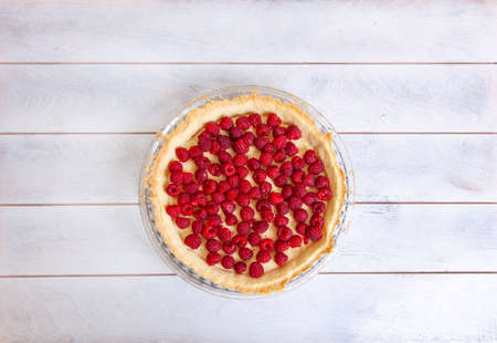 Preparation of shortbread pie with raspberries on white wooden background, top view.