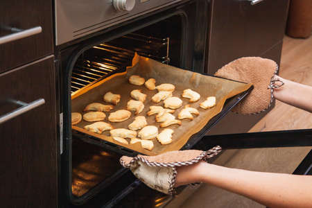 Woman opens the oven where cookies are baked for Halloween.の写真素材