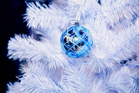 Blue Christmas balls hangs on white artificial fir tree.の写真素材