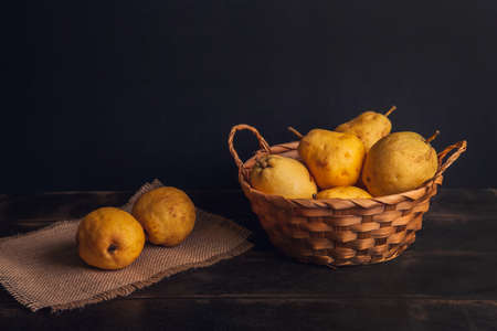 Natural pear fruit with defects in a basket on a jute napkin and a dark wooden background.の写真素材