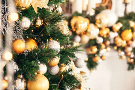 Gold and silver Christmas toys, balls garlands on a spruce branch with copy space.の写真素材