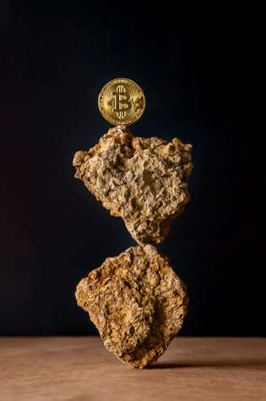 Golden Bitcoin Coin balances on natural stones on a dark background. Blockchain cryptocurrency, store of value.の写真素材