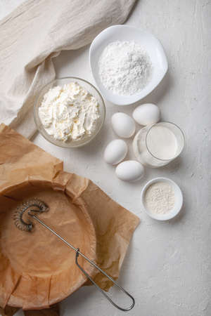 Ingredients for making Basque Spanish burnt Saint Sebastian cheesecake. Cream cheese, sugar, eggs, flour, cream, baking dish covered with paper. Recipe step by step flat lay top viewの写真素材