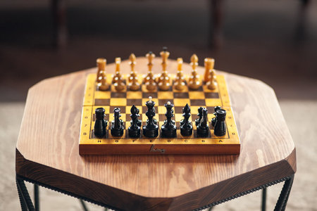 Wooden chess pieces on a board game, on a wooden polygonal vintage table, selective focus.の写真素材