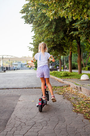 A girl of 8 years old rides an rented electric scooter in the park. Kick scooter sharingの写真素材