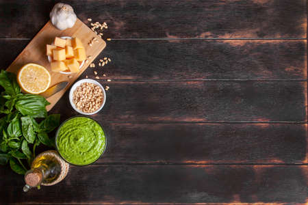 Pesto sauce in a glass bowl and ingredients for making basil sauce at home. Flat lay top view on...