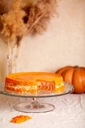 Homemade cottage cheese and pumpkin casserole with poppy seeds and orange on a glass stand on the table with pumpkins and reeds.の写真素材