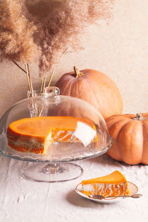 Homemade cottage cheese and pumpkin casserole with poppy seeds and orange and cut piece on a glass stand and pumpkins.の写真素材