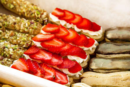 Gastronomic box with sweet eclairs with cheese mousse and fresh berries, chocolate-coated cream,...